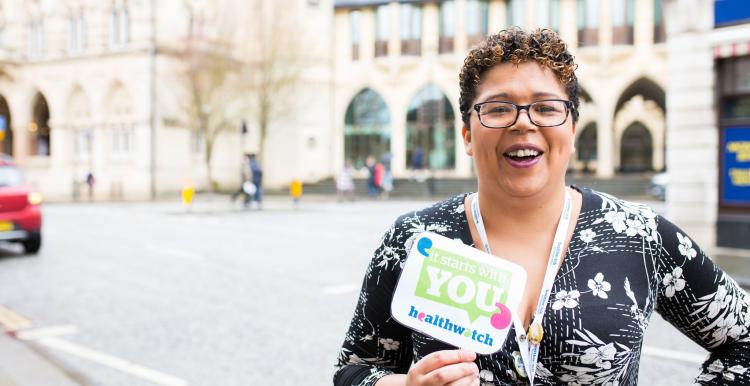 Healthwatch staff member holding an It Starts With You sign to promote the campain