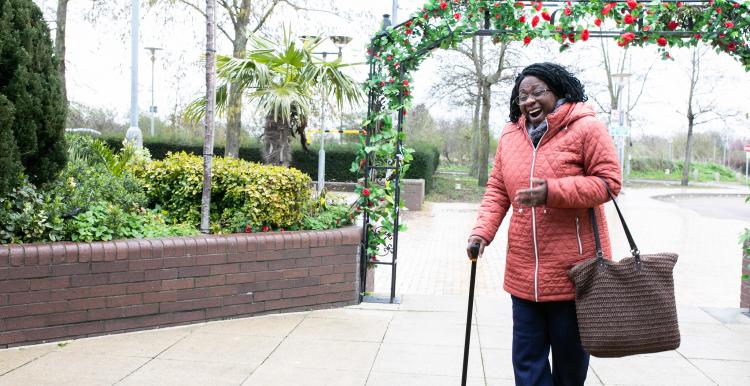 Happy smiling woman in a park after walking through an arch of Roses