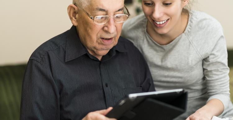 Woman helping an elderly man use a IPad