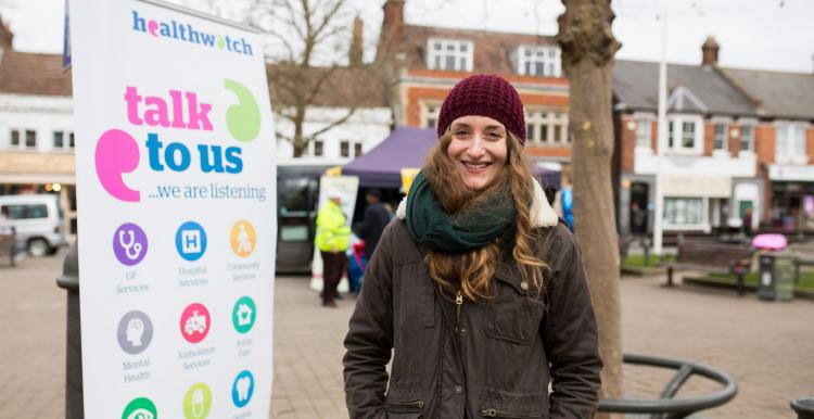 Student volunteer standing infront of a Healthwatch banner