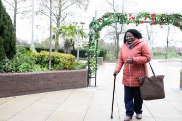 Happy smiling woman in a park after walking through an arch of Roses