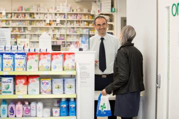 Women reading advice and information leaflet by advice stand