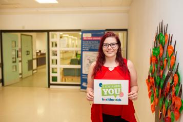 woman holding it starts with you campaign poster in foyer