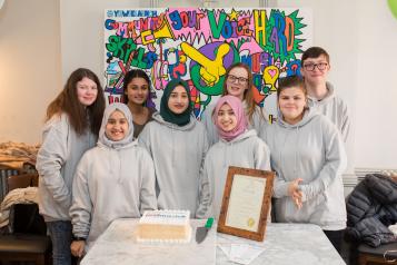 Group of young volunteers with certificate and cake